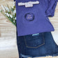 Purple shirt with 'Girl Mom' embroidery on a wooden surface with flowers.