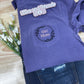 Purple t-shirt with 'Girl Mom' design on a wooden surface with flowers.